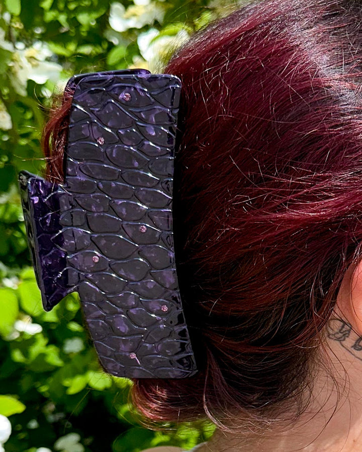 Dragon scale hair accessory with purple pearlescent swirls and dark purple gems for fantasy readers.