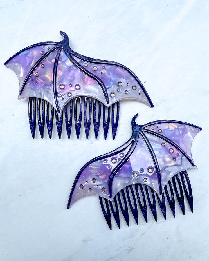 Hair combs for fantasy fans featuring two purple combs in the shape of dragon wings with engraved embellishments and a pearlescent purple color.