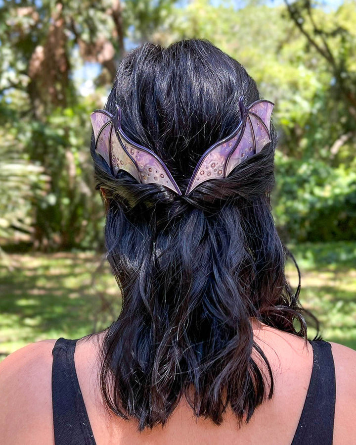 Hair combs for dragon lovers featuring two large combs in the shape of dragon wings with engraved details and a pearlescent purple color.