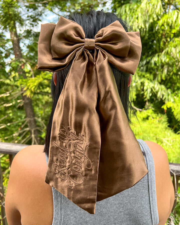 Cowboy romance hair bow made with brown satin and embroidered elements.