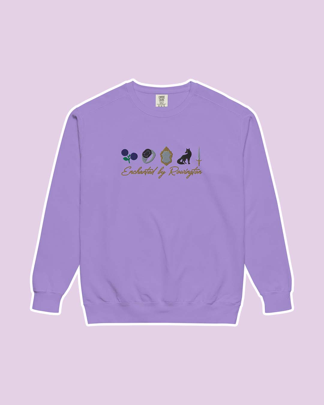 Violet sweatshirt for Enchantra fans featuring the phrase 'Enchanted by Rowington' in gold script text below five illustrated elements including demonberries, a ring, a mirror, a fox, and a sword.