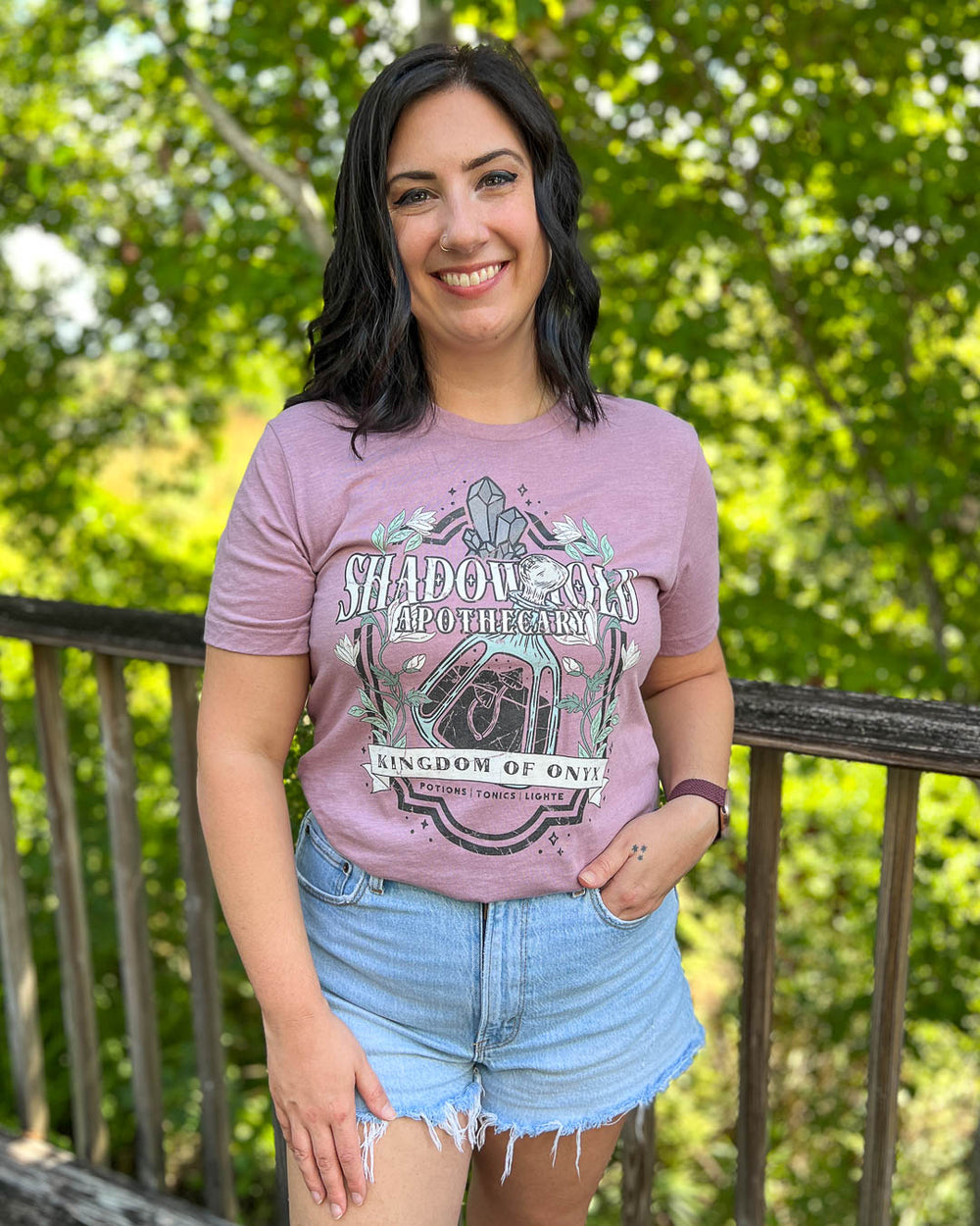 The Sacred Stones shirt with a Shadowhold Apothecary design of a potion, gems, flowers, and stars.