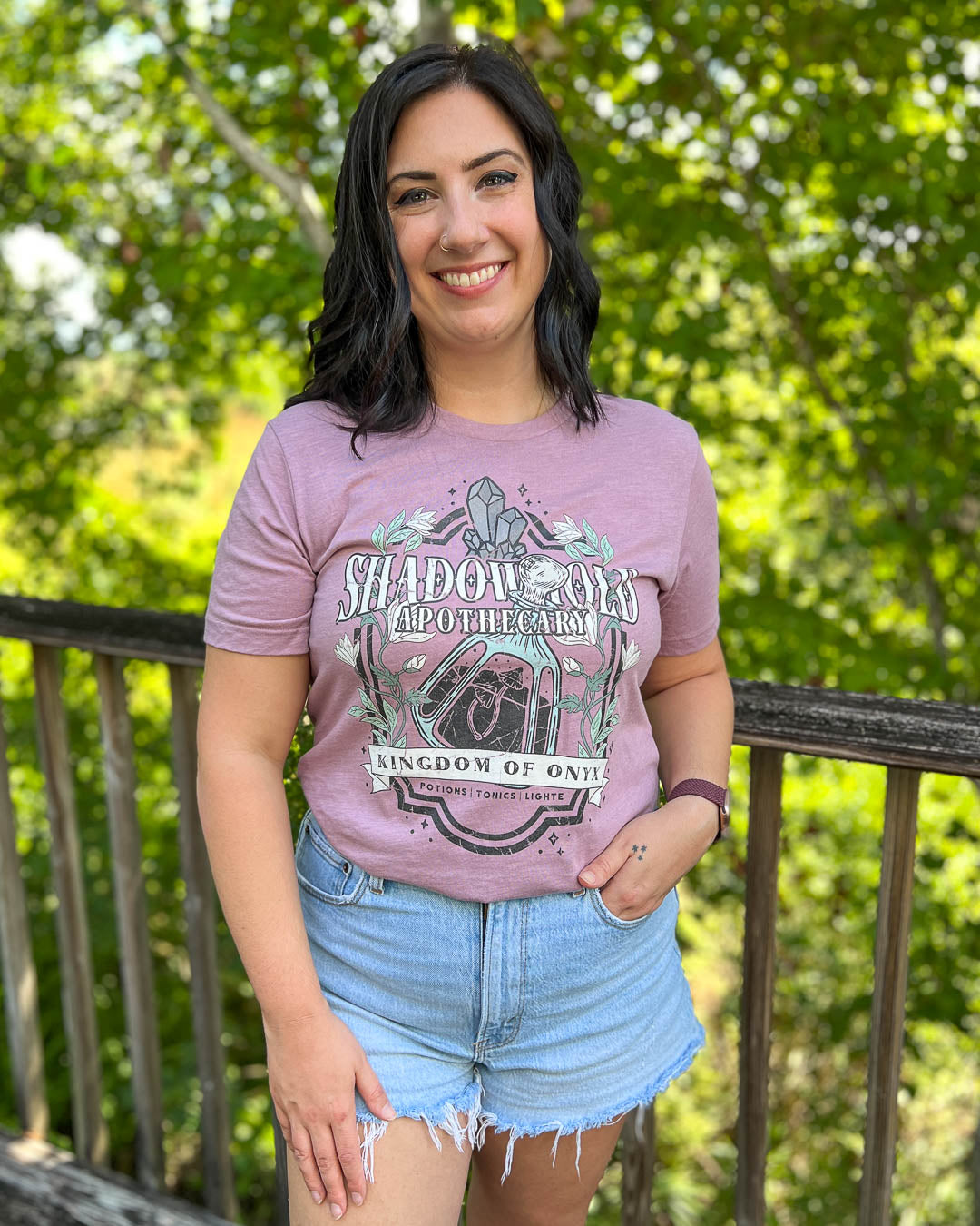 The Sacred Stones shirt with a Shadowhold Apothecary design of a potion, gems, flowers, and stars.