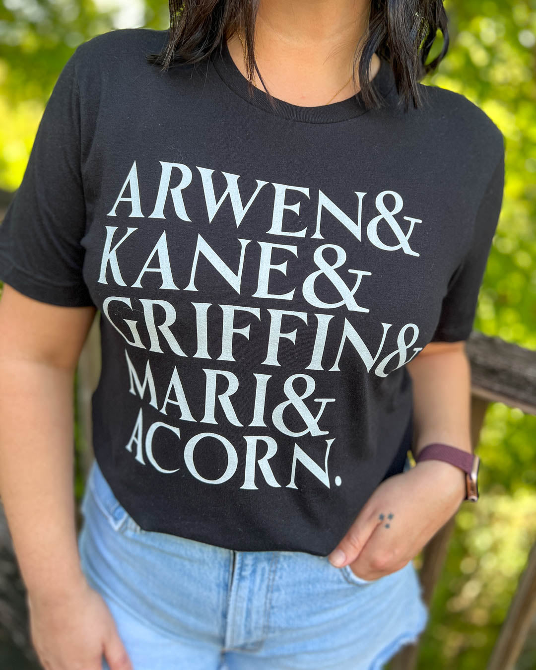A Dawn of Onyx tee listing the names of the main characters in the Sacred Stones series including Arwen, Kane, Griffin, Mari, and Acorn in white on a black shirt.