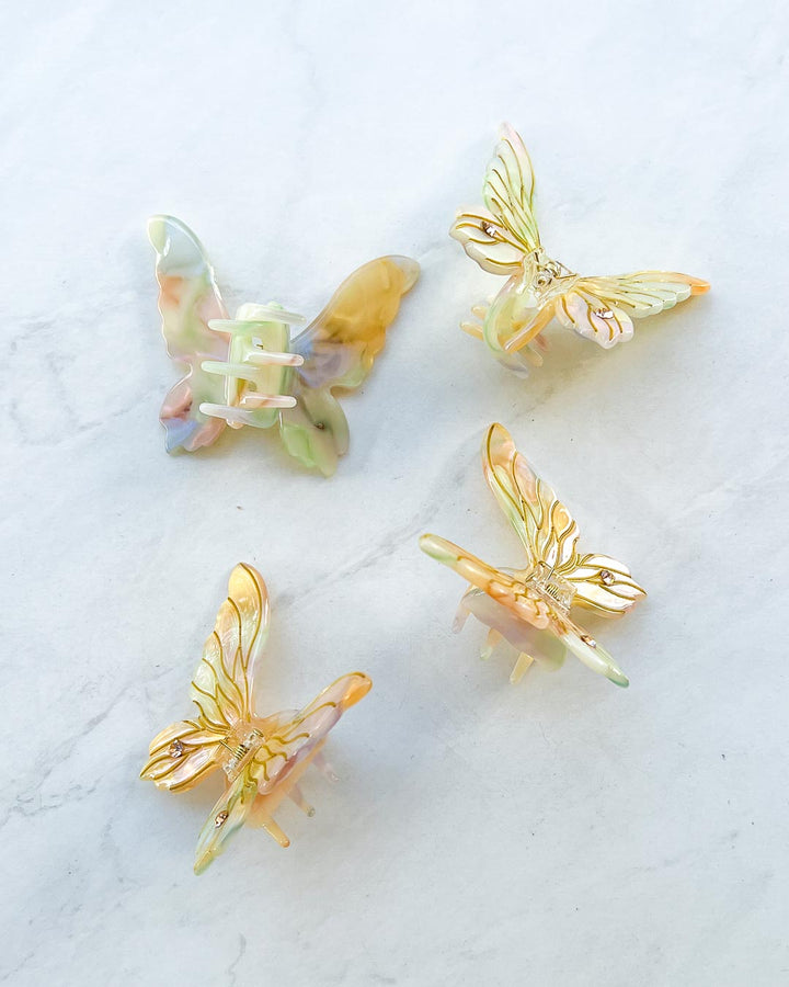 Fantasy mini hair clips featuring fairy wing accessories in iridescent gold. 