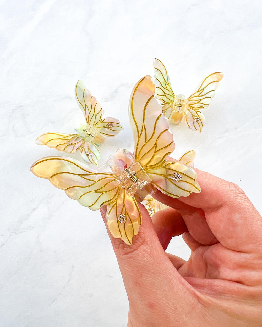 Ren faire hair clips in iridescent gold with gem embellishments in the shape of mini fairy wings.