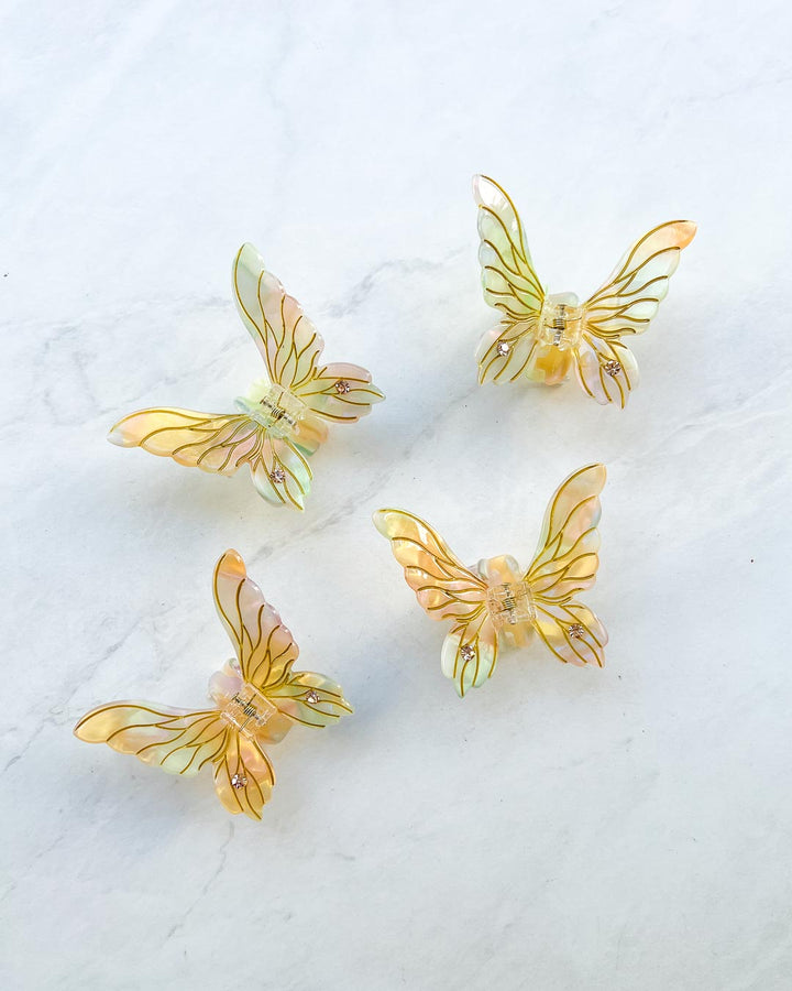 Four gold iridescent fairy mini claw clips in the shape of fairy wings with etching details and gems.