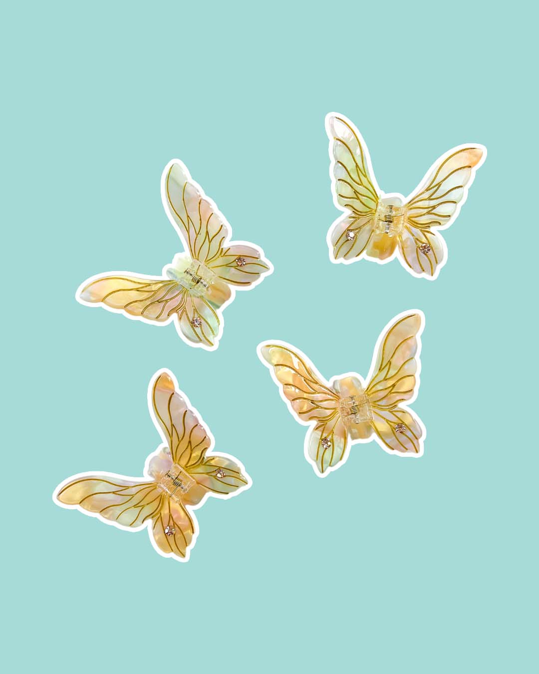 Fantasy hair mini claw clips in iridescent gold with etching details and gem embellishments in the shape of fairy wings.