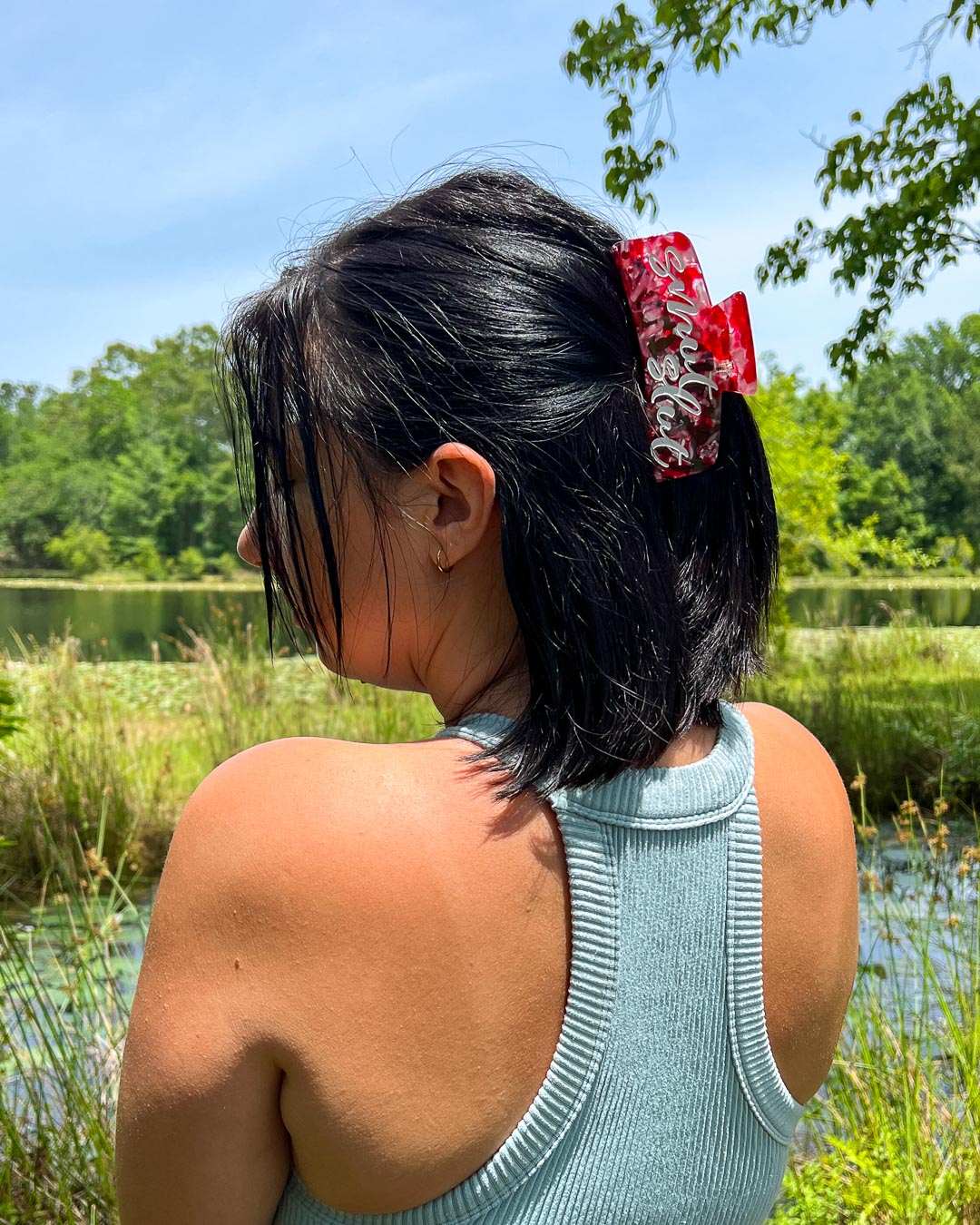 Hair clipped half-up-half-down with a red, pink, and transparent bookish hair clip for romance readers with white text saying &