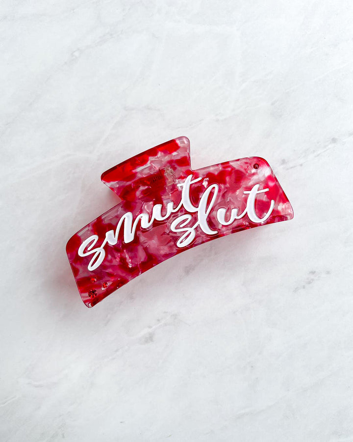 Romance reader hair clip with red, white, and transparent detailing and white script font on the hair accessory saying &