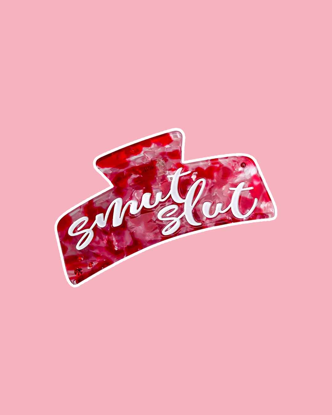 A bookish hair claw clip with a red, pink, and transparent marbled design and script font saying 'smut slut.' 
