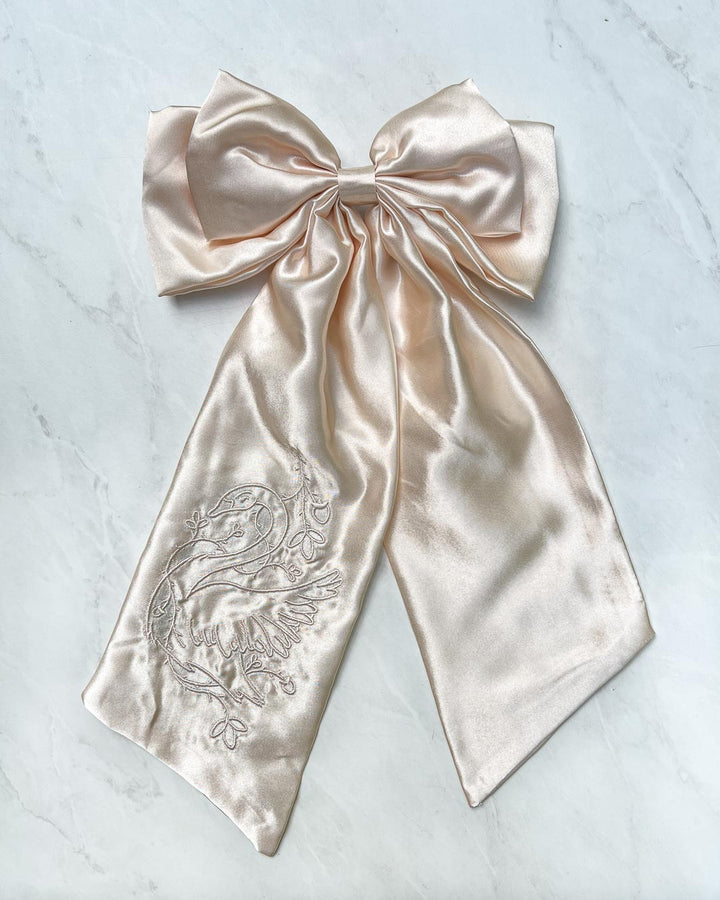 Ivory hair bow for romantasy fans featuring a swan wrapped in ivy embroidered on the accessory.
