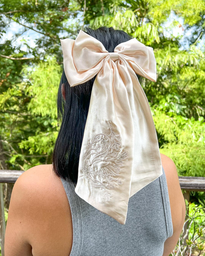 Bookish hair accessory with shiny, ivory satin and a swan wrapped in ivy embroidered on the hair bow. 