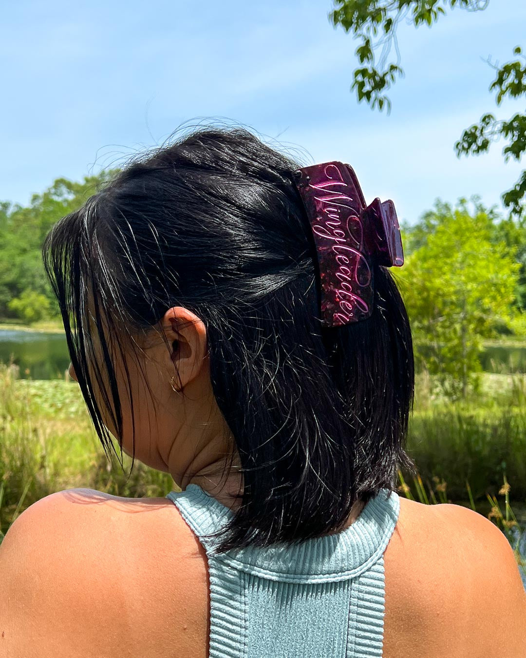 Hair clipped half-up-half-down with a maroon pearlescent bookish hair clip for fantasy readers with pink text saying &
