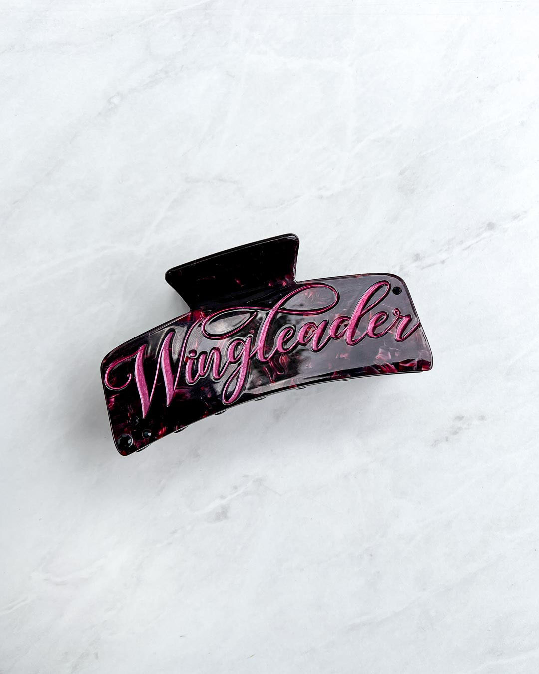 Wingleader hair clip with maroon pearlescent detailing and pink script font on the hair accessory.