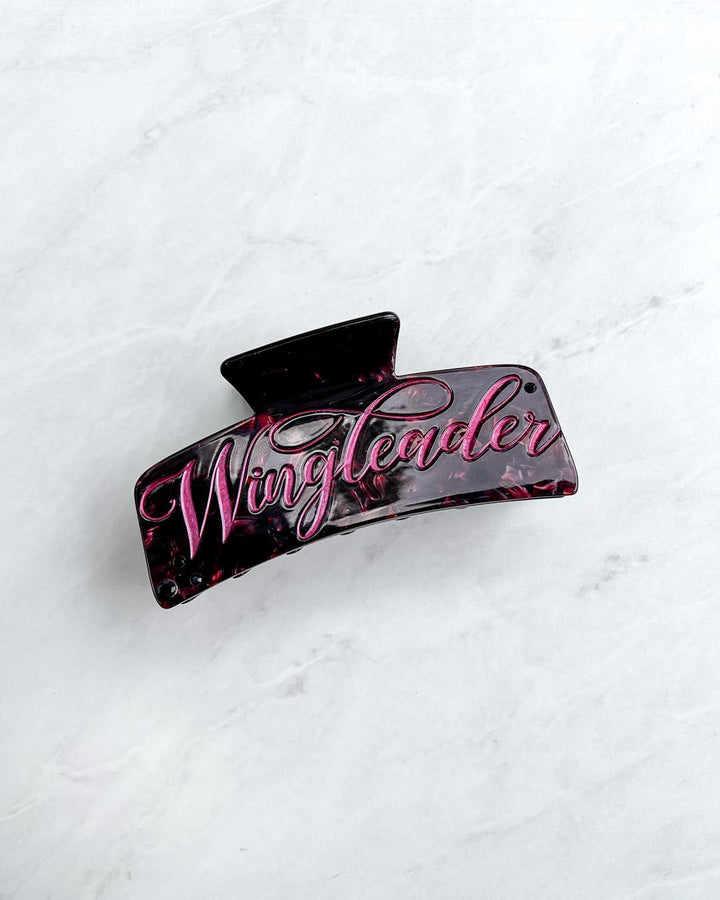 Wingleader hair clip with maroon pearlescent detailing and pink script font on the hair accessory.