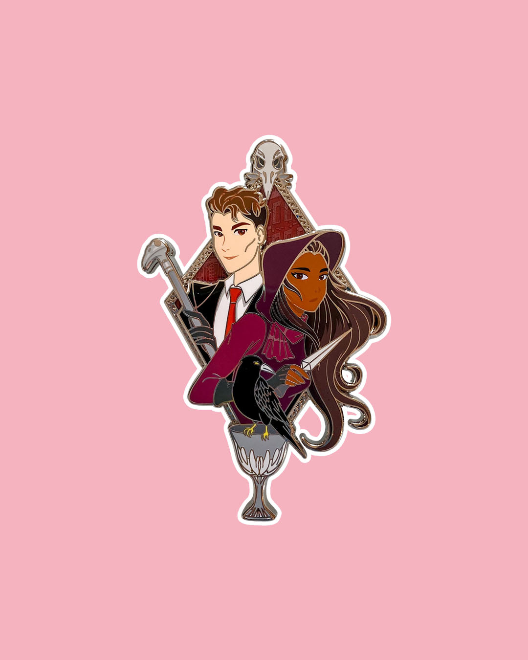 Six of Crows enamel pin featuring an illustrated design of Kaz and Inej complete with a cane, a dagger, and a crow.