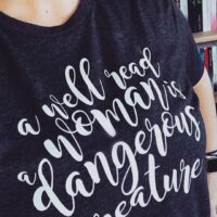 person taking a selfie wearing a the a well read woman in a dangerous creature boyfriend tee