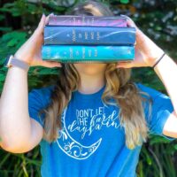 person holding ACOTAR books wearing blue don't let the hard days win boyfriend tee