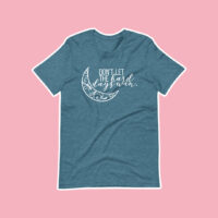 Don't Let the Hard Days Win Flat Lay Shirt Inspired by A Court of Thorns and Roses by Sarah J Maas on pink background showing teal shirt with moon design and cursive font