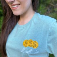 Girl wearing a robin's egg blue colored shirt with embroidered design reading "ctrl+shift+c motherlode".