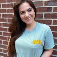 Girl wearing a robin's egg blue colored shirt with embroidered design reading "ctrl+shift+c motherlode".