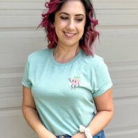 person wearing sky diamond farms tee shirt with the strawberry pocket print showing standing against a white wall looking to the side