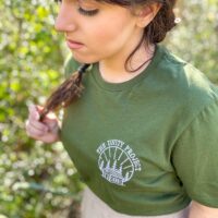 Person wearing a green shirt with an embroidered design reading "the unity project".
